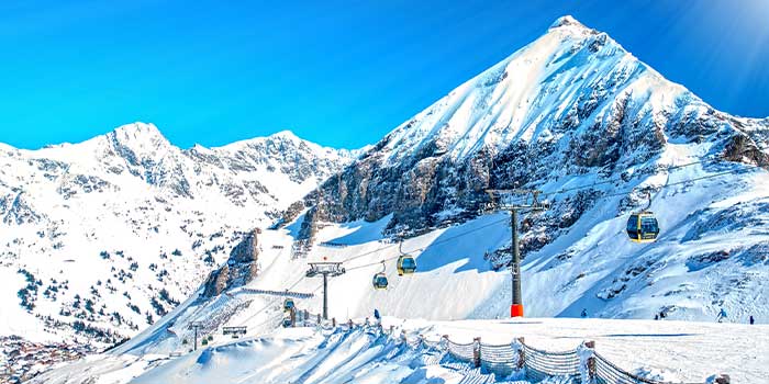 Eine verschneite Berglandschaft mit Skiliften und einem klaren blauen Himmel.