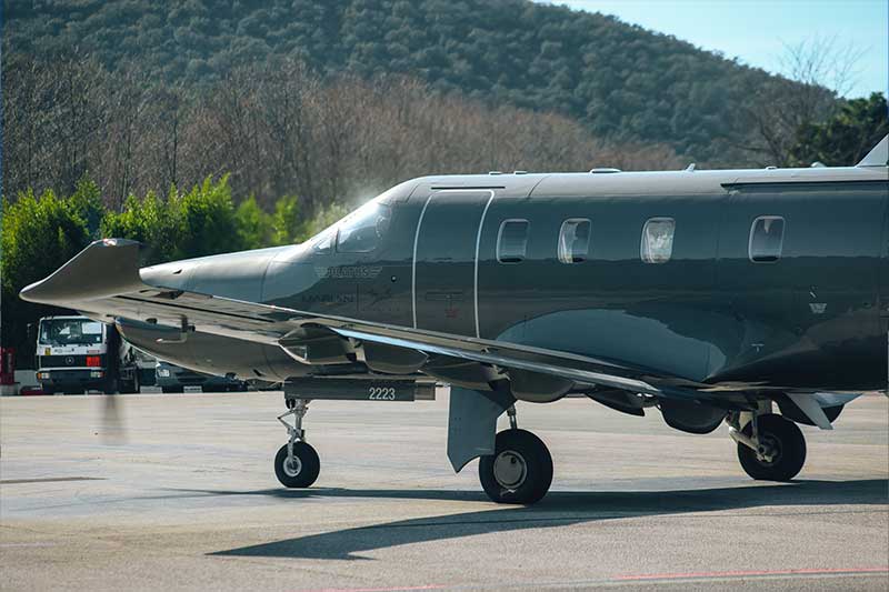 Auf dem Rollfeld parkt ein kleiner Privatjet, im Hintergrund ist eine Hügellandschaft zu sehen.