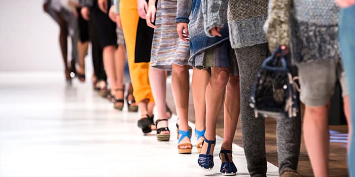 Models laufen auf einem Laufsteg und präsentieren verschiedene Outfits und Schuhe.